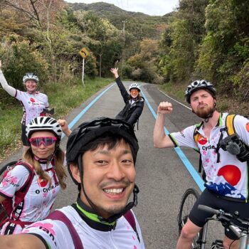 Five excited cyclists some with their hands or fists in the air to show their excitement after concurring a hill climb.