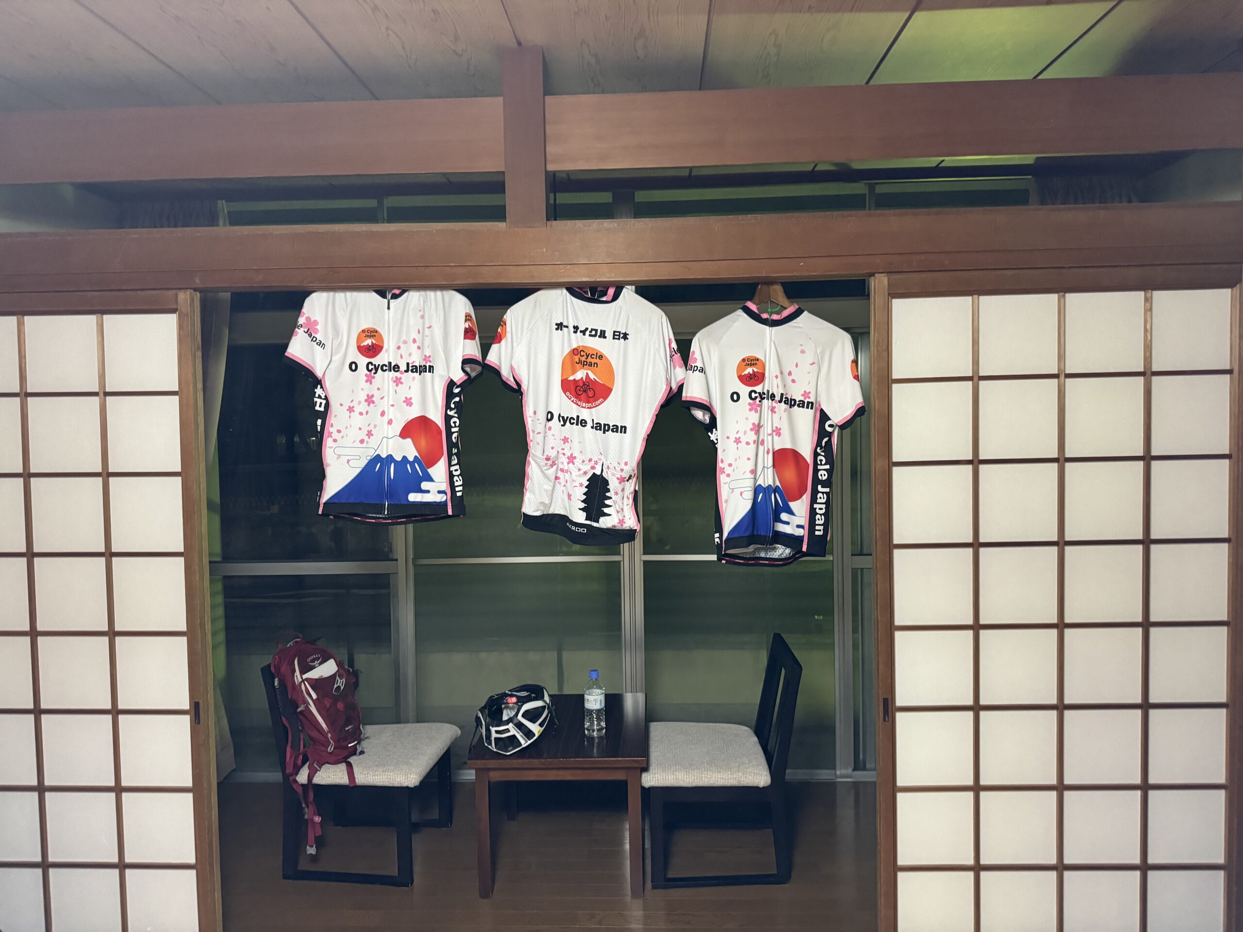 Three O Cycle Japan jersey's hang in the sitting area of a local Ryokan with paper doors on either side of a small sitting room.