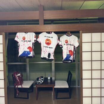 Three O Cycle Japan jersey's hang in the sitting area of a local Ryokan with paper doors on either side of a small sitting room.