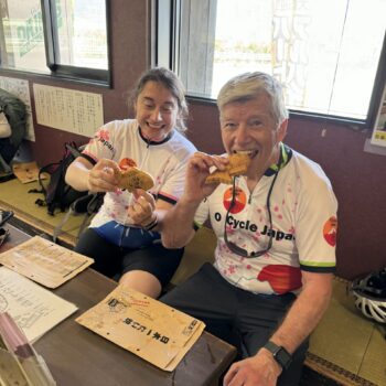 Two cyclist eating fish shaped pastry, Taiyaki, in a local shop.