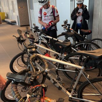 Bikes lined up inside a building with two bikers looking over the bikes in anticipation.