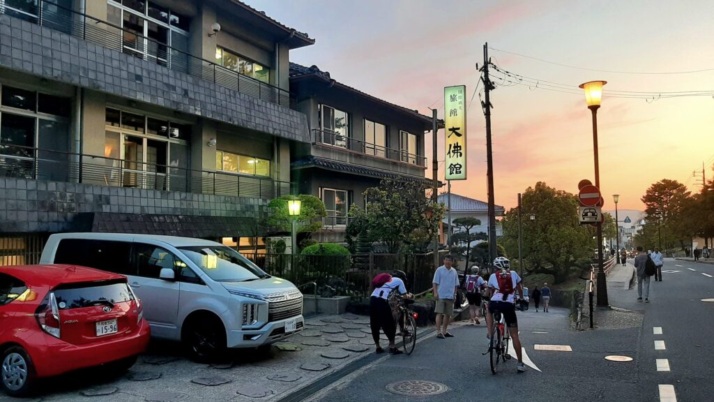 Sun setting on hotel with cyclists arriving at traditional Japanese Ryokan hotel.