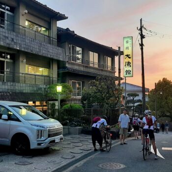 Sun setting on hotel with cyclists arriving at traditional Japanese Ryokan hotel.