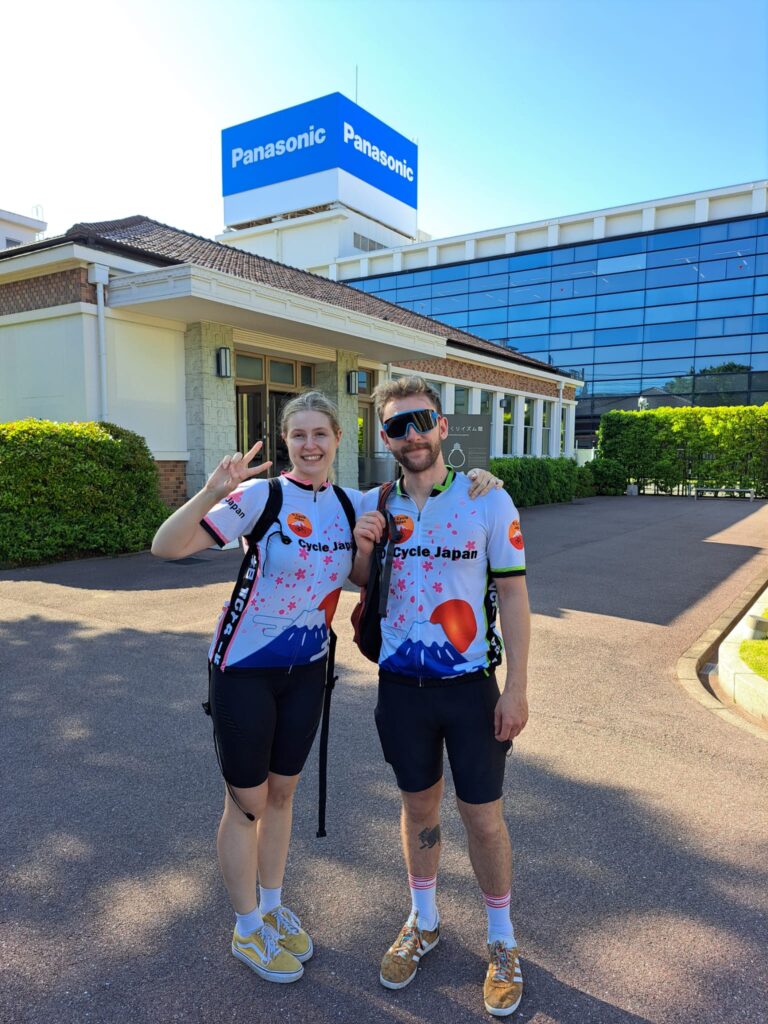 Couple of cyclists pose in front of Panasonic Museum in Osaka.