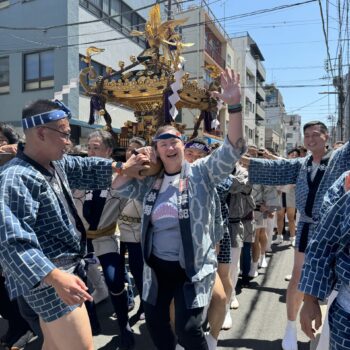 Girl with hand in the air carries Japanese float festival with group of others.