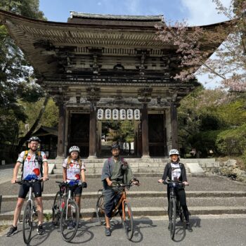 Miidera temple Otsu gate in background with 4 cyclists posing in front of the entrance.