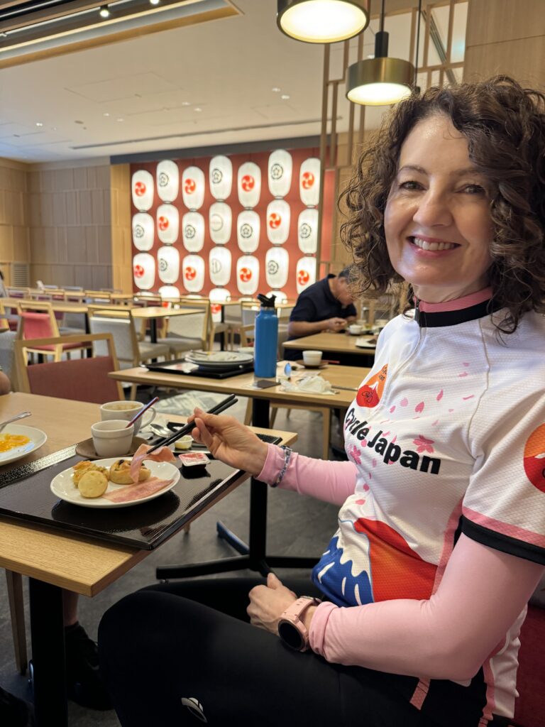 Woman smiles as she enjoys her breakfast. Paper lanterns in white, orange and grey are in the background.