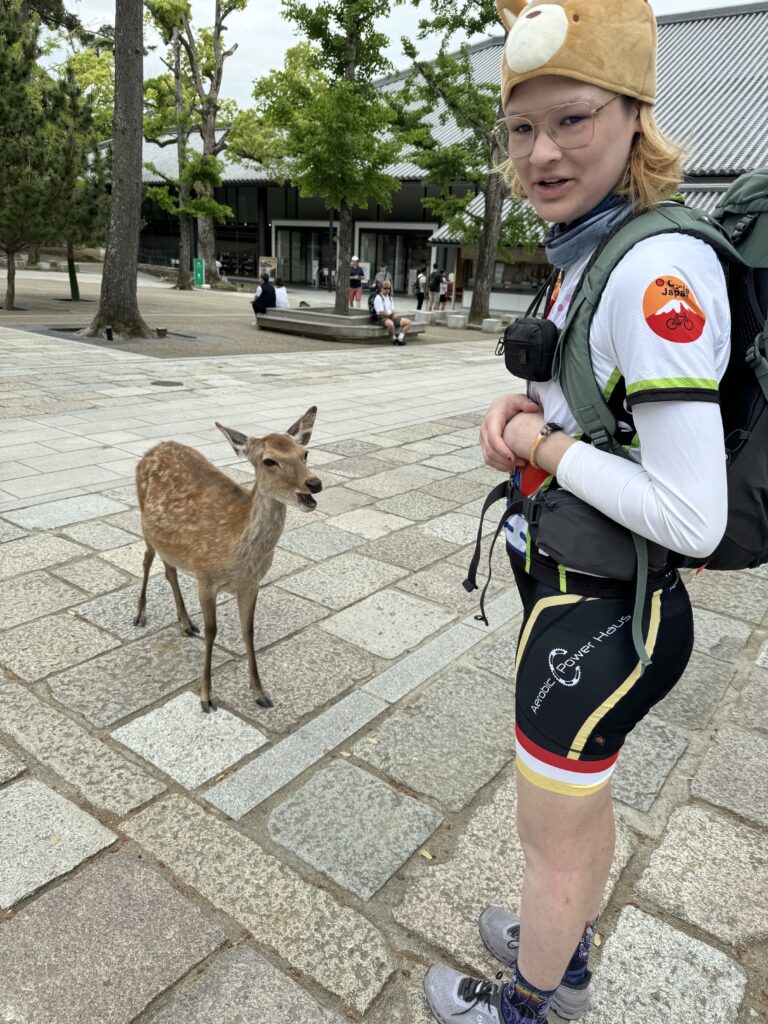 Cyclist in deer hat poses with deer in Nara.