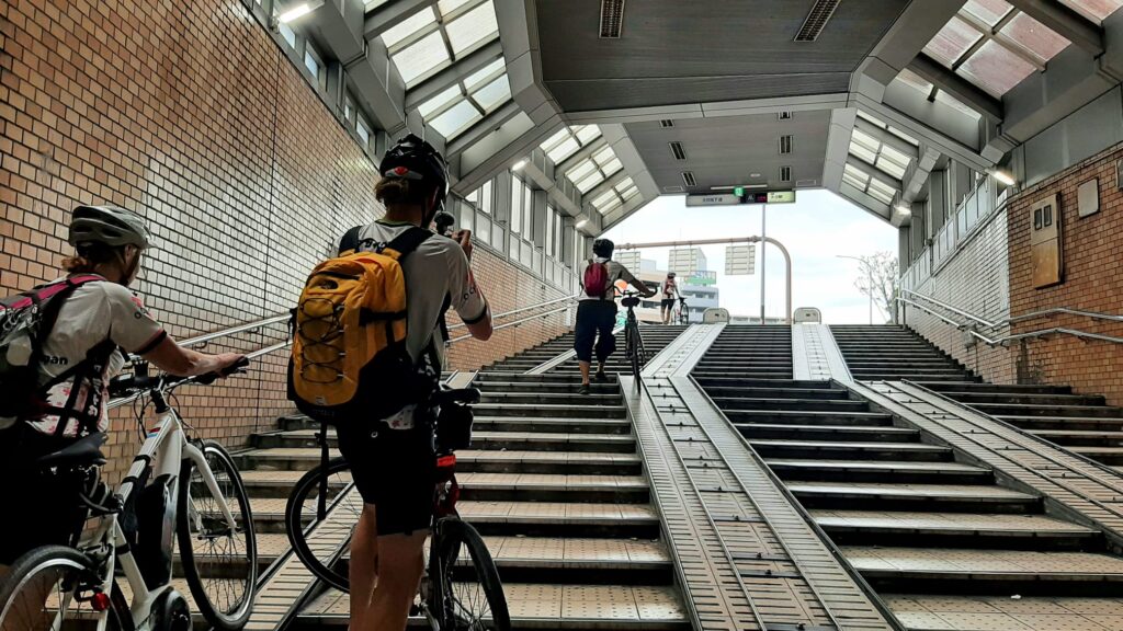 Cyclists push their bike up a ramp in an underground pedestrian tunnel.