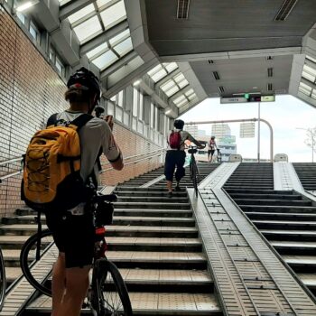 Cyclists push their bike up a ramp in an underground pedestrian tunnel.