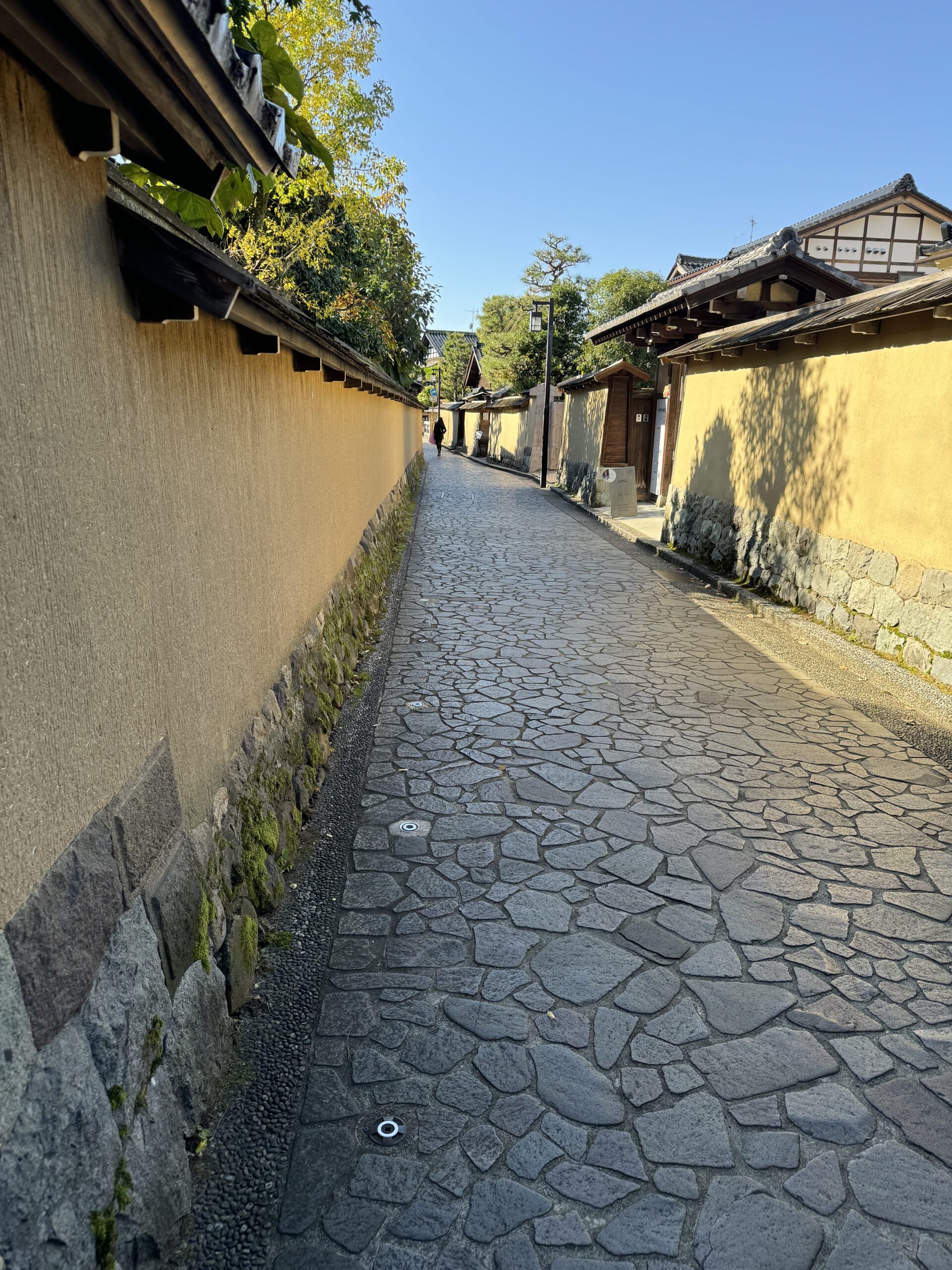 Quiet street in Kanazawa that showcases the cobble street and yellow walls.