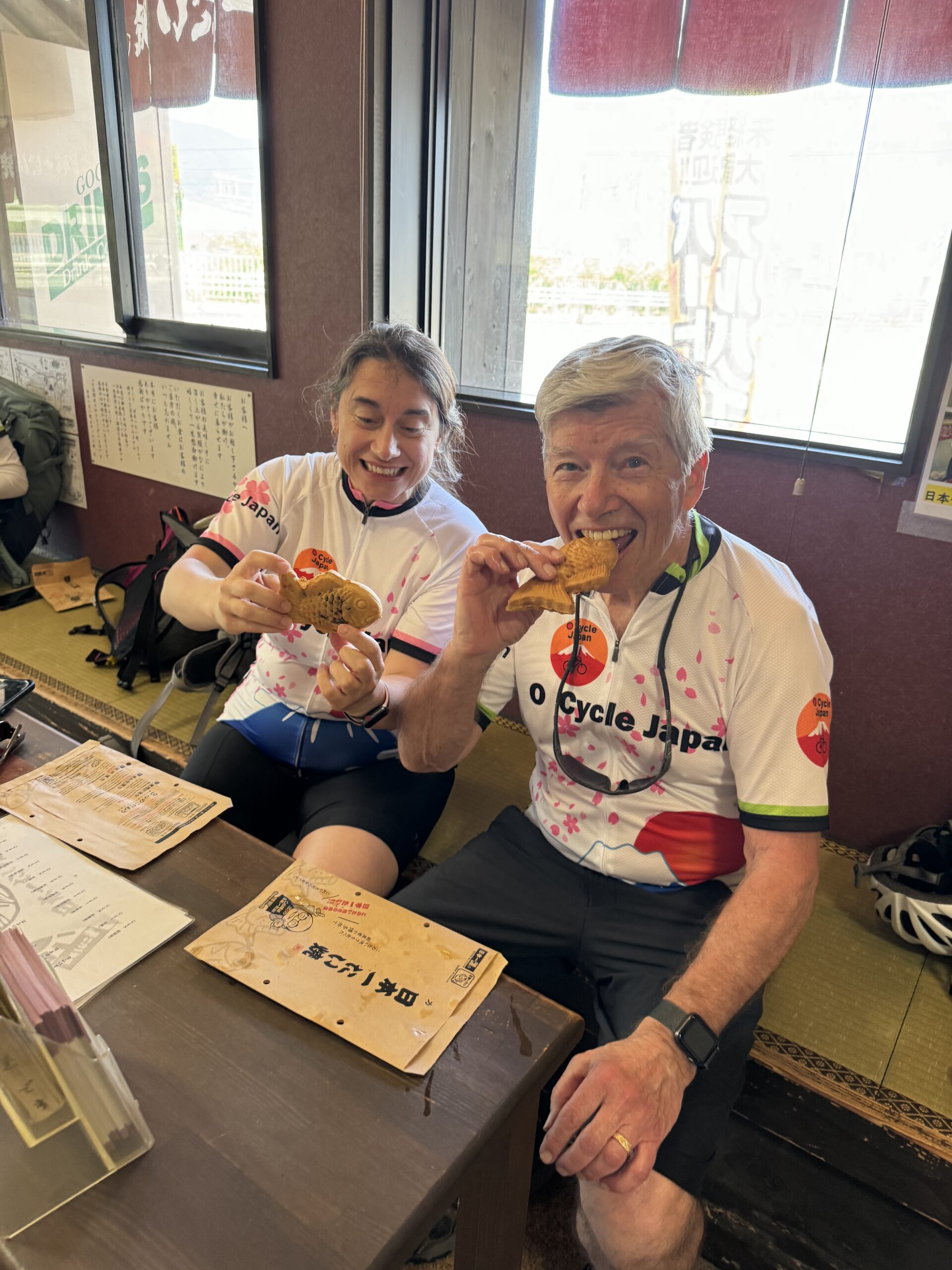 Two cyclists take a break and enjoy Taiyaki a fish shaped pastry filled with red beans or custard.