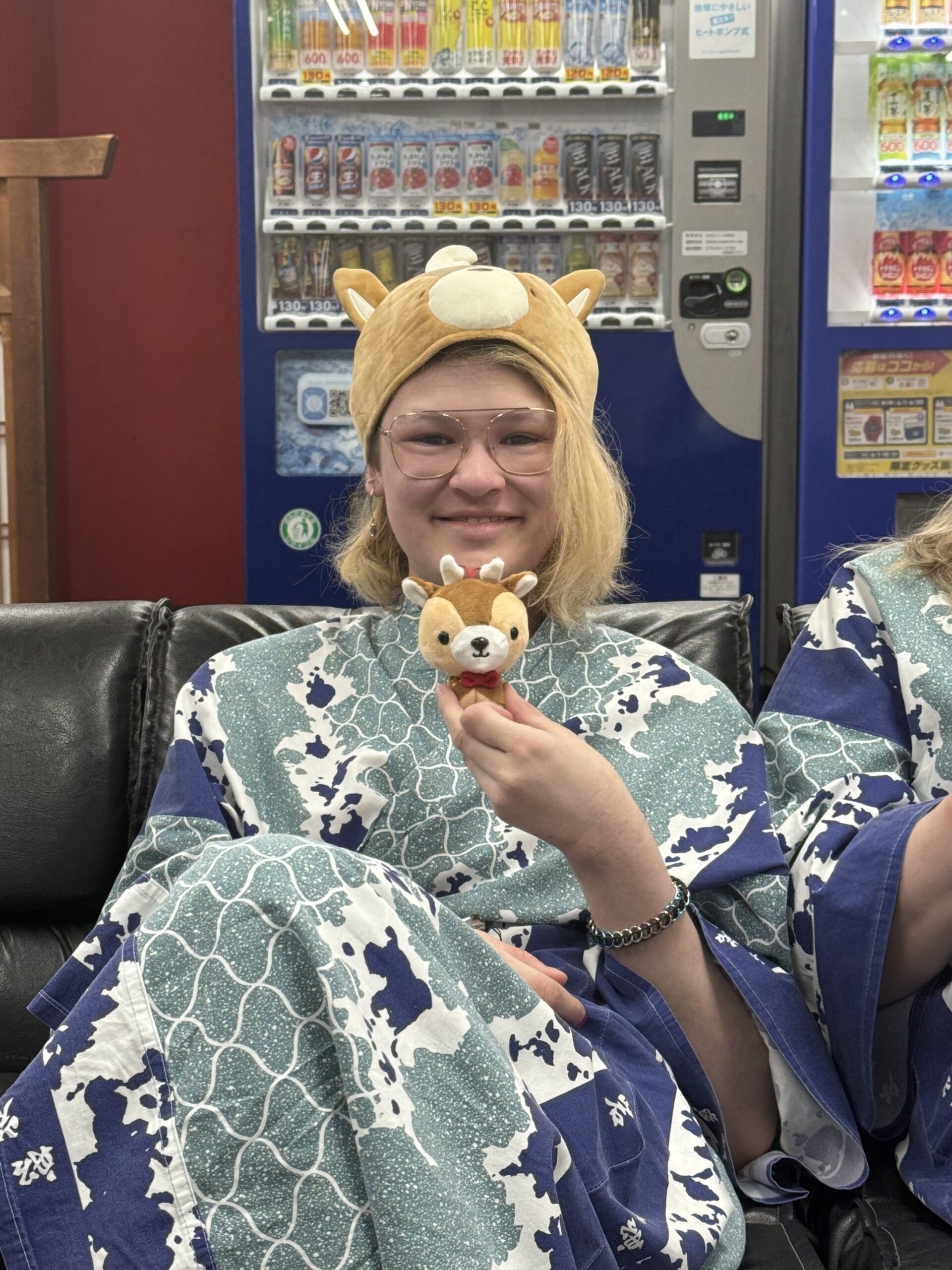 Girl sits in hotel lobby with vending machine in the background posing with a small stuffed deer momentum.