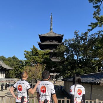 Three cyclists admire a 5 story pagoda in the background.