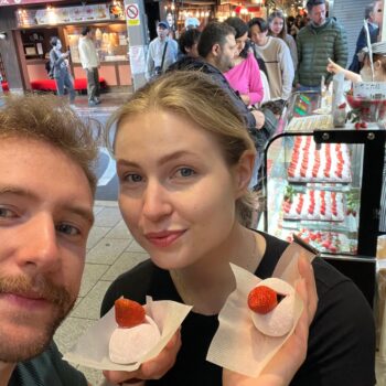 Couple shows off their strawberry mochi treat, a sweet dessert street food.