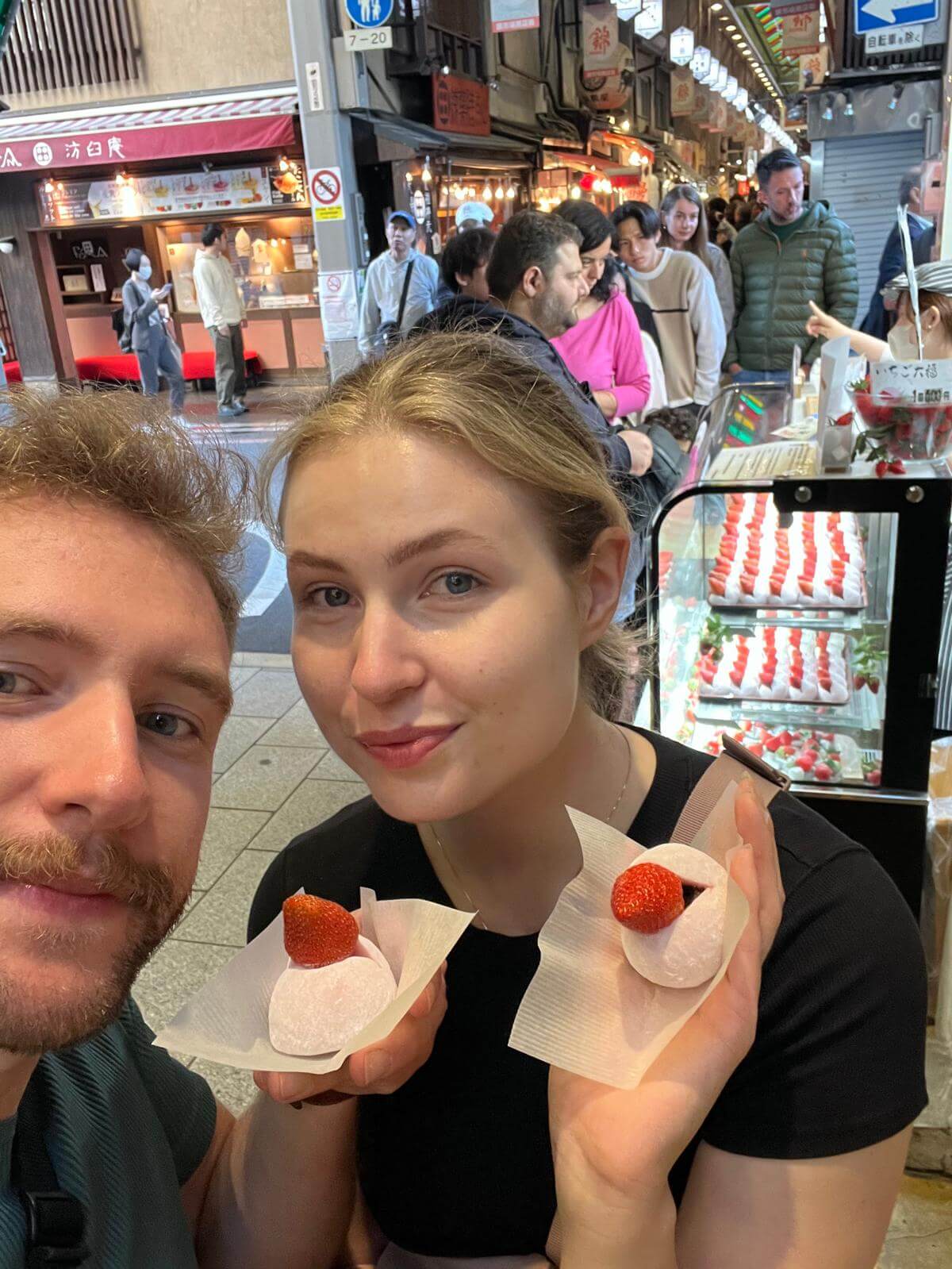 Couple shows off their strawberry mochi treat, a sweet dessert street food.