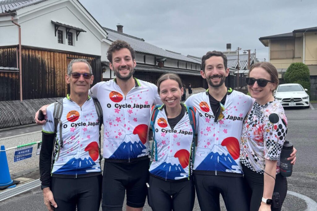 Group of cyclists smiling in front of Gekkeikan sake museum.