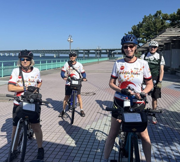Four cyclists pose for picture while on their bikes in Rinku Town, Osaka, Japan.